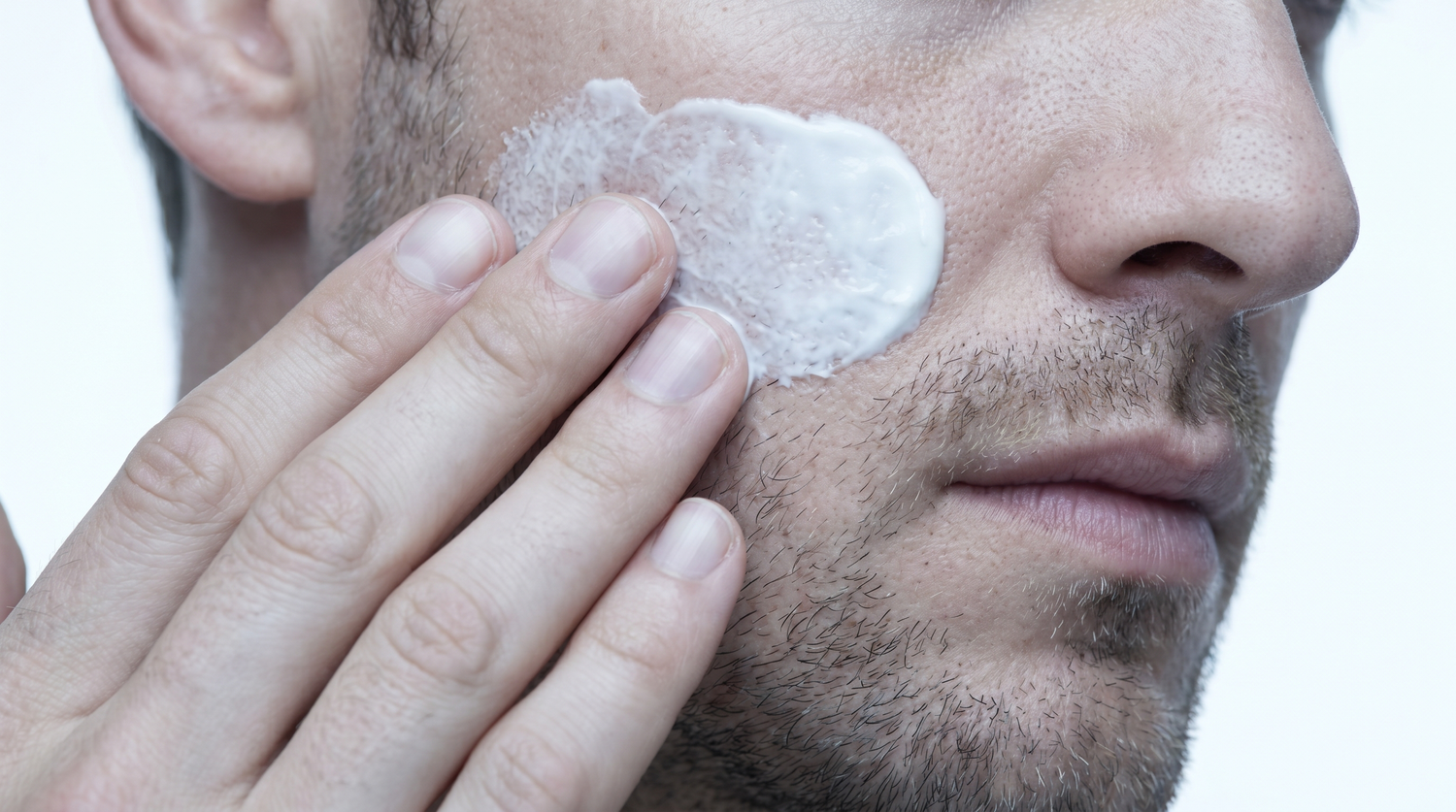 Mani maschili che applicano crema sul viso, skincare clinica Remodermis